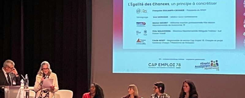 Scène des 30 de CAP Emploi 78 - IHY au Campus Oxygène Factory – Les Mureaux. 1 homme debout au pupitre, 1 femme debout à coté lisant son texte, 4 femmes assises, 1 présentation projetée en arrière plan sur l'écran