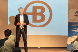 Intervention de Nicolas Potier au Café Rencontres de l'ADEZAC. Monsieur Potier sur scène, debout. En arrière plan logo Bruneau diffusé sur écran projecteur.