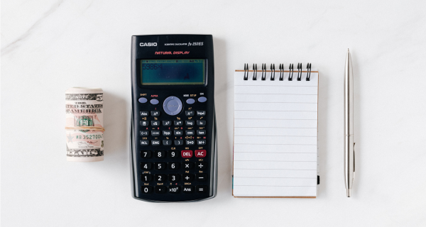 Illustration de l'article sur le calcul du coût du salaire en france par le geyvo groupement d'employeurs : de l'argent liquide, une calculatrice casio, un bloc note et un crayon