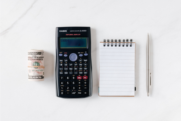 Illustration de l'article sur le calcul du coût du salaire en france par le geyvo groupement d'employeurs : de l'argent liquide, une calculatrice casio, un bloc note et un crayon